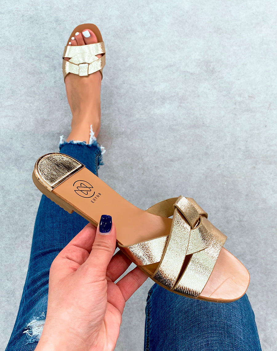 Mules dorées plates à bride entrecroisées et à détail dorée et noir