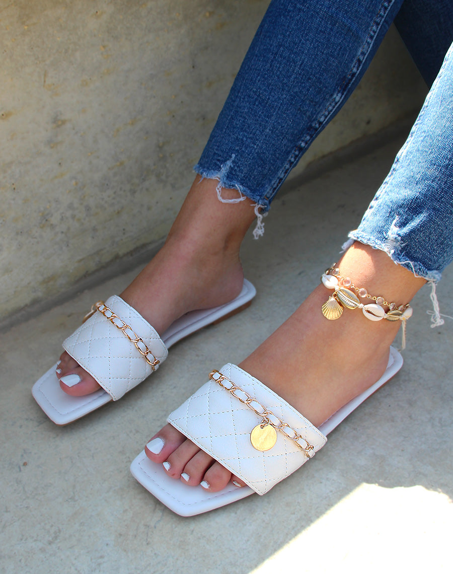 Mules plates blanches matelassées à fine chaine dorée et bout carré
