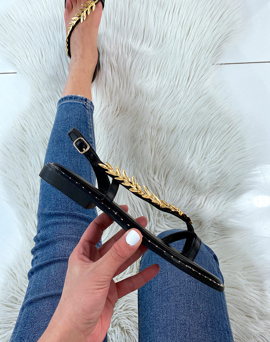 Nu-pieds noirs ornés d’un bijou doré en forme de laurier