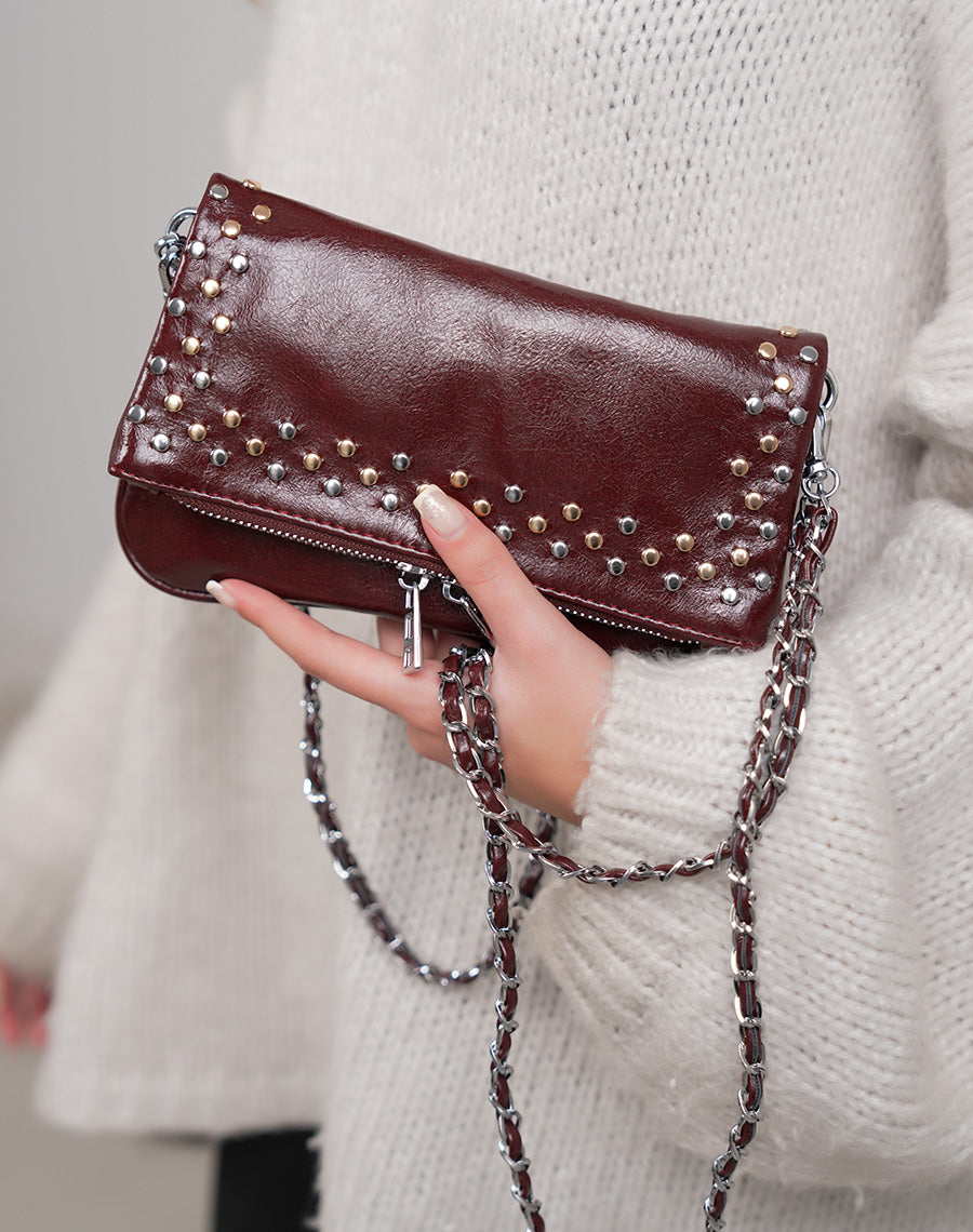 Sac pochette femme bordeaux brillant avec clous décoratifs et fermeture zippée argentée