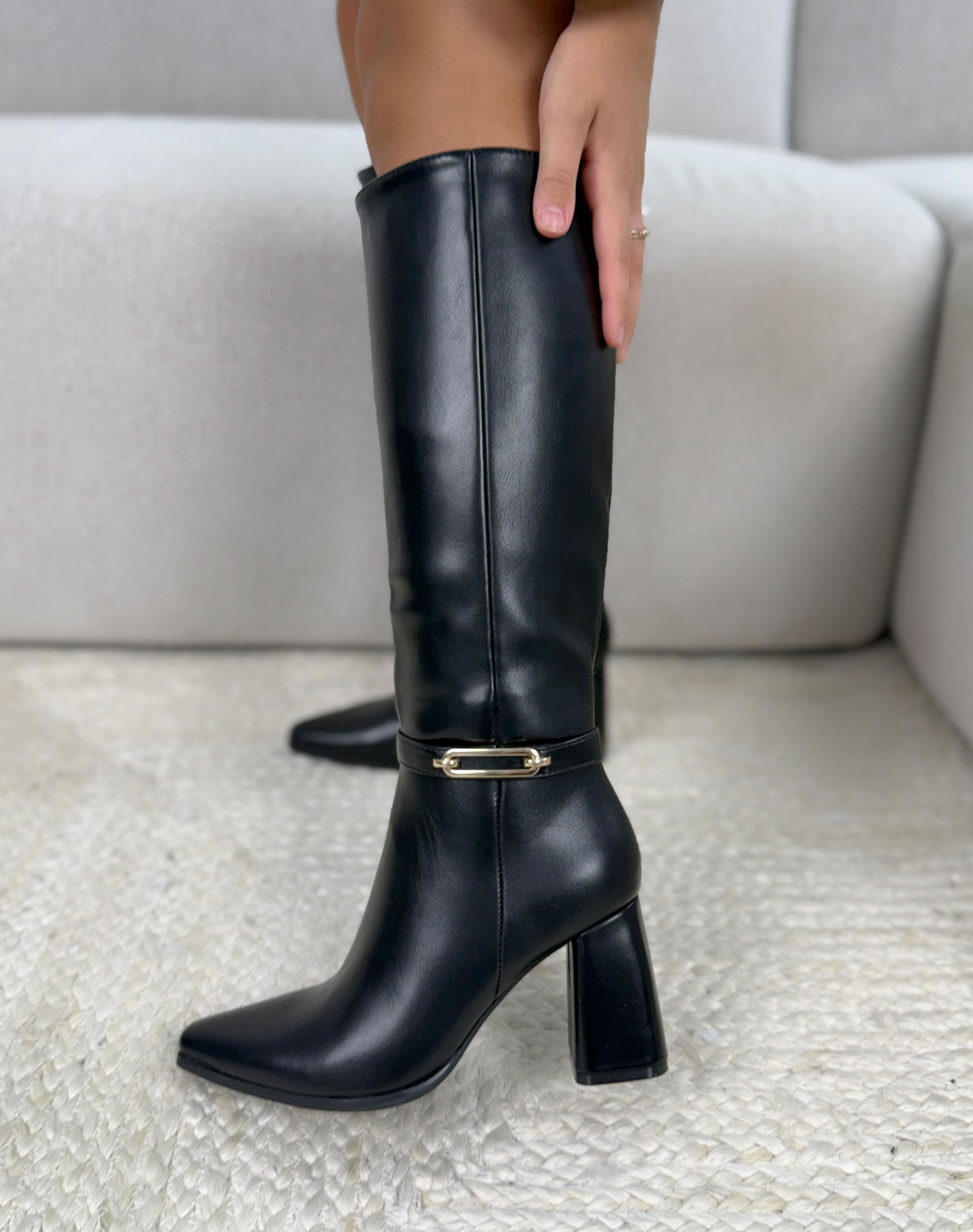Bottes noires à sangle décorative à boucle dorée à bout pointu et talon épais.