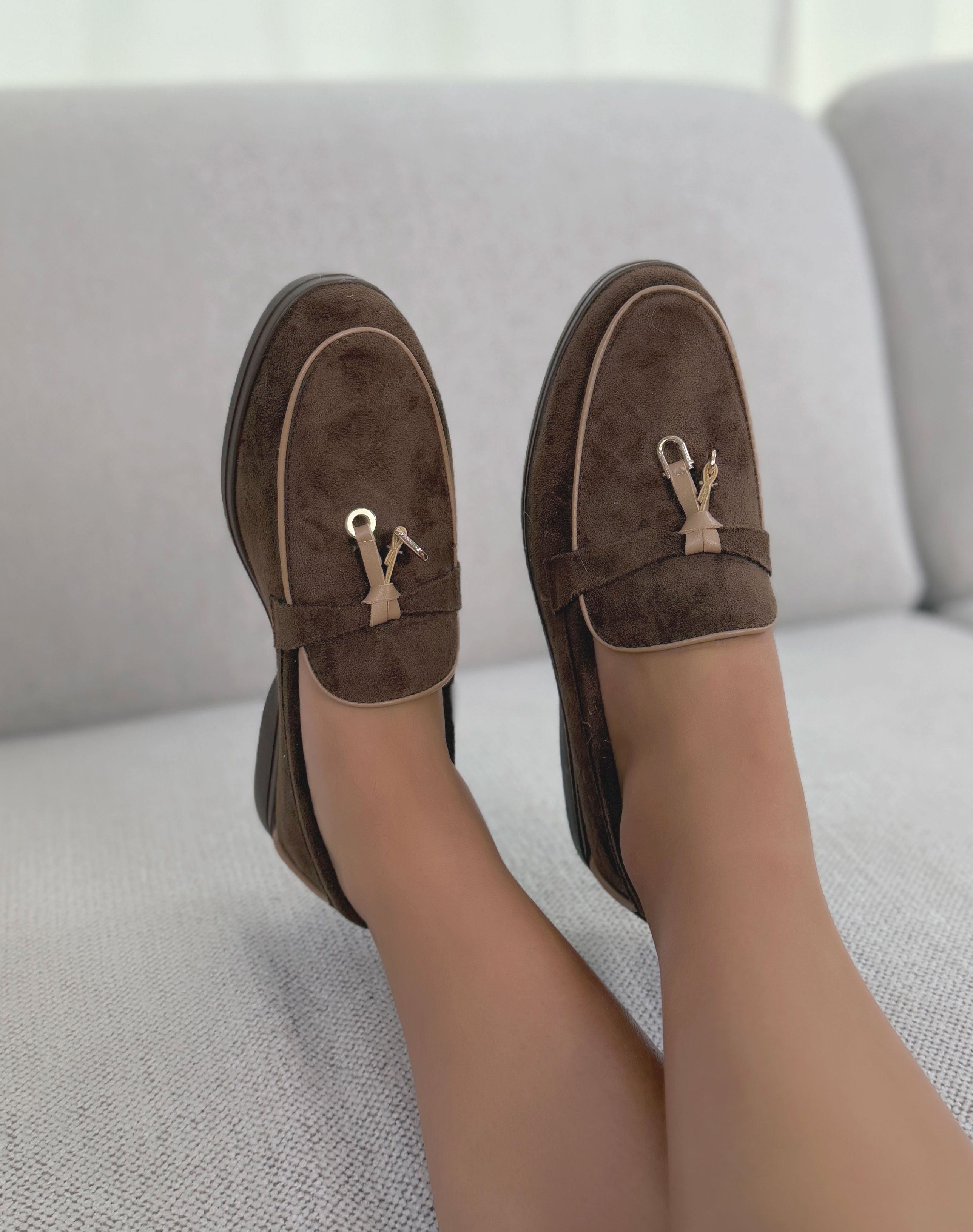 Mocassins marron en suédine avec détail beige foncé et doré avec semelle plate.