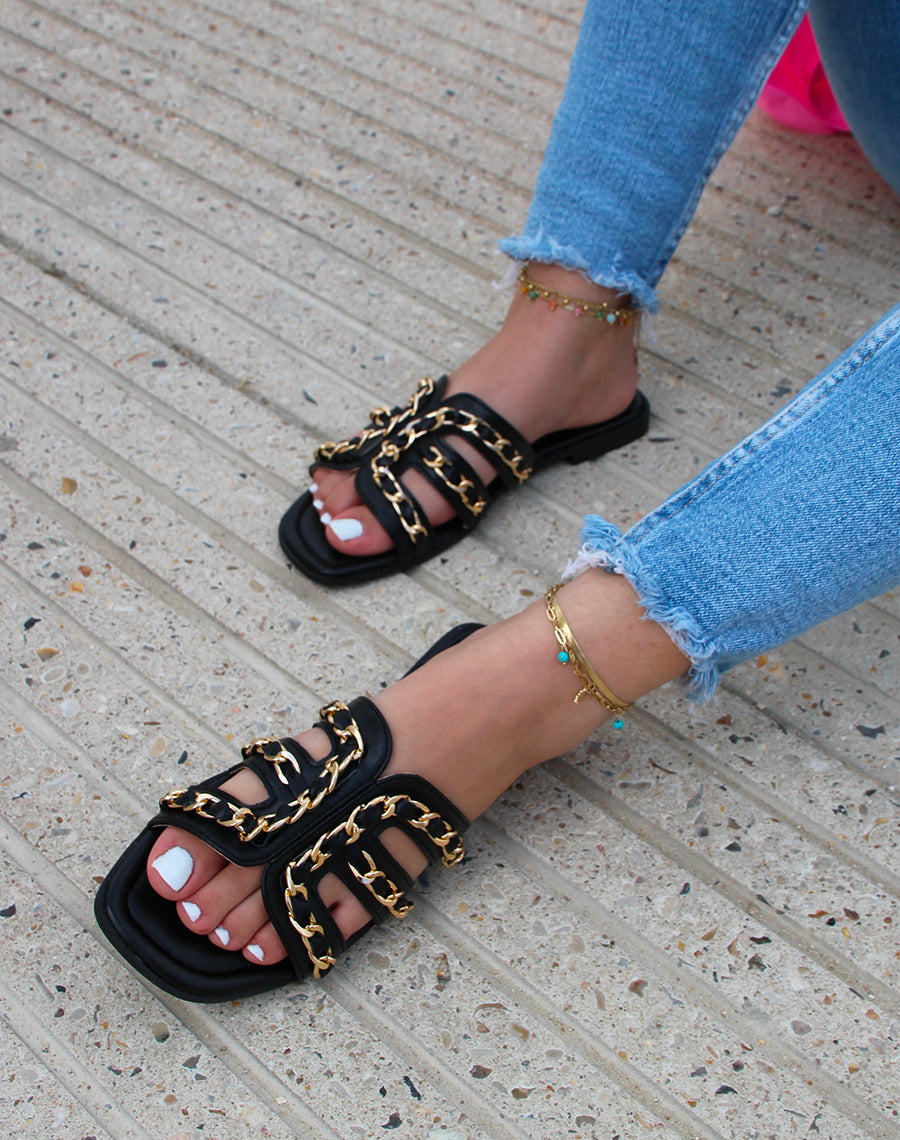 Mules noires à brides ouvertes croisées à chaîne dorée