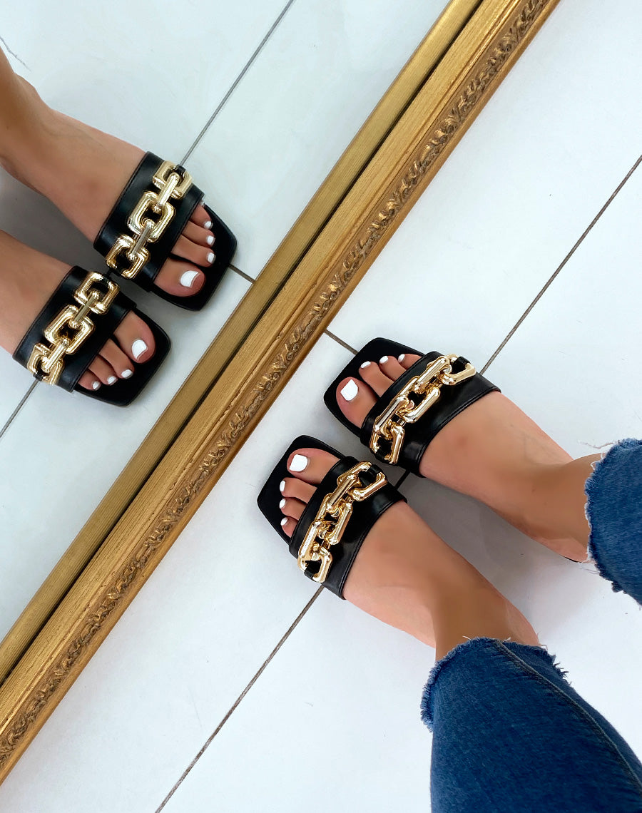 Mules noires plates à grosse chaîne dorée et bout carré